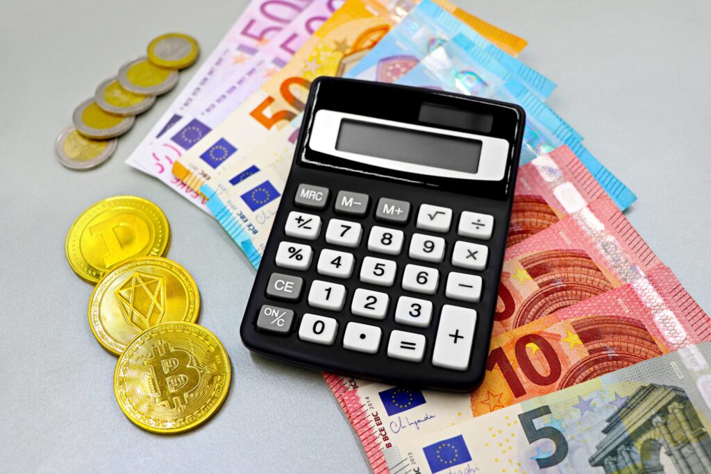 Calculadora y monedas sobre una mesa para organizar trucos de ahorro mensual.
