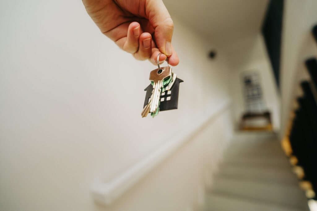 Mano sosteniendo unas llaves con llavero de casa en un pasillo que ilustra el acceso al mercado del alquiler de vivienda en España.