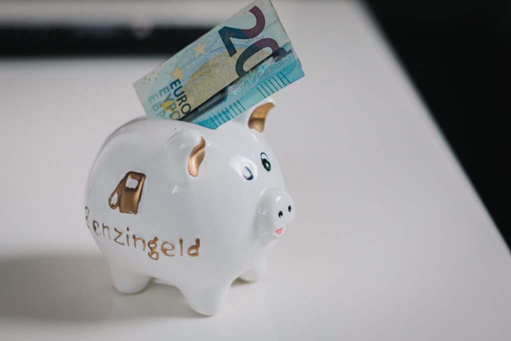 Hucha de cerdito blanca con un billete de 20 euros para el ahorro mensual y minimalismo financiero.