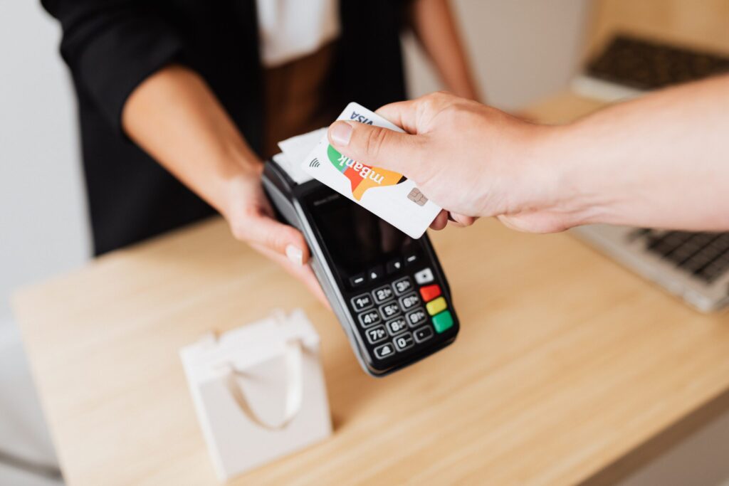 Mano utilizando un terminal de pago digital para realizar una transacción financiera sin comisiones.
